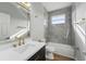 Modern bathroom with marble tile, dark vanity with gold fixtures, and shower-tub combo at 11508 Delwick Dr, Windermere, FL 34786