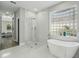 Bathroom featuring a walk-in shower, free standing tub, and glass block window at 11508 Delwick Dr, Windermere, FL 34786