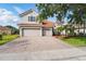View of the home's facade showing the three-car garage, brick-paved driveway, and manicured lawn at 11508 Delwick Dr, Windermere, FL 34786