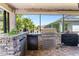 Outdoor kitchen with stone counter, built in grill, refrigerator and storage at 1204 Lexington Ave, Davenport, FL 33837