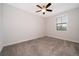 A bright bedroom featuring neutral carpet, ceiling fan, and large window at 1227 Sandwedge St, Davenport, FL 33896