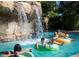 Community pool features a rock waterfall where people are lounging on inner tubes on a sunny day at 1370 Centre Court Ridge Dr # 204, Reunion, FL 34747