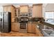 Modern kitchen featuring wood cabinetry, stainless steel appliances, granite countertops, and sleek black refrigerator at 14208 Morning Frost Dr, Orlando, FL 32828