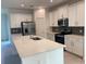 Modern kitchen with white cabinetry, a large island with sink, and sleek stainless steel appliances for cooking at 14746 Erice Ave, Clermont, FL 34714