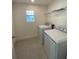 Well-lit laundry room equipped with a washer, dryer, shelving and tiled floor, offering convenience and efficiency at 14746 Erice Ave, Clermont, FL 34714
