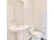 A stylish powder room features a pedestal sink, toilet and a large framed mirror at 1504 Oak Marsh Loop, Davenport, FL 33837
