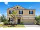 Two-story home with a two-car garage, a palm tree, and neutral-colored exterior with brown shutters at 1504 Oak Marsh Loop, Davenport, FL 33837