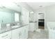 Bathroom featuring double vanities with stone countertops, a soaking tub, and a glass enclosed shower at 15849 Sweet Lemon Way, Winter Garden, FL 34787