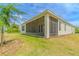 Exterior rear shot of a home with a screened in porch and lush green yard with landscaping at 1598 Whitewood Ct, Kissimmee, FL 34747