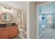 Well-lit bathroom with a wood vanity, granite countertop, and a walk-in shower at 16163 Pebble Bluff Loop, Winter Garden, FL 34787