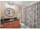 Bathroom featuring a granite countertop, wooden vanity, floral shower curtain, and unique mirror at 16163 Pebble Bluff Loop, Winter Garden, FL 34787