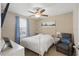 Bright bedroom featuring a ceiling fan, window with blinds, and a plush armchair at 16163 Pebble Bluff Loop, Winter Garden, FL 34787