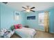 Bedroom with blue walls, white bed, ceiling fan and chair at 16163 Pebble Bluff Loop, Winter Garden, FL 34787