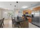 Modern kitchen with stainless steel appliances, wooden cabinetry, and an island with barstool seating at 16163 Pebble Bluff Loop, Winter Garden, FL 34787