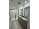 Bright bathroom features double sinks with granite countertops, tile flooring, and a glass-enclosed shower at 16468 Happy Eagle Dr, Clermont, FL 34714