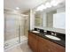 Well-lit bathroom with double vanity, granite countertop, and glass-enclosed tiled shower at 16518 Brook Springs Aly, Winter Garden, FL 34787