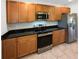 Well-equipped kitchen featuring stainless steel appliances, black granite countertops, and wood cabinetry at 16518 Brook Springs Aly, Winter Garden, FL 34787
