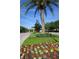 Scenic view of community entrance with manicured landscaping, colorful flowers, and a grand gatehouse at 1724 Cottonwood Creek Pl, Lake Mary, FL 32746