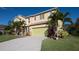 Two-story home with a light yellow exterior, a green two car garage door, and tropical landscaping at 207 Black Springs Ln, Winter Garden, FL 34787