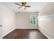 This quaint bedroom includes a ceiling fan, a window, and dark hardwood flooring at 2411 Sabastian St, Mount Dora, FL 32757