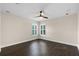 A bright bedroom is illuminated by a ceiling fan, two windows, and dark hardwood flooring at 2411 Sabastian St, Mount Dora, FL 32757