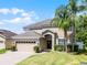 Charming two-story home with a well-maintained lawn, brick driveway, and mature trees at 2411 Sabastian St, Mount Dora, FL 32757