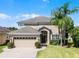 Inviting two-story home with a lush green lawn, brick driveway, and beautiful landscaping at 2411 Sabastian St, Mount Dora, FL 32757