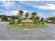 Community welcome sign with lush landscaping, featuring palm trees, shrubbery, and vibrant green grass at 2411 Sabastian St, Mount Dora, FL 32757