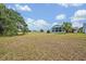 Large grassy backyard featuring mature trees and a view of the home with a screened-in porch, perfect for outdoor enjoyment at 25057 Riverwalk Dr, Leesburg, FL 34748