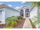 Inviting front entrance showcasing landscaped garden beds, stucco walls, and a secure screened entry at 25057 Riverwalk Dr, Leesburg, FL 34748