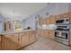 Open kitchen with stainless steel appliances and light-colored wooden cabinetry at 25057 Riverwalk Dr, Leesburg, FL 34748