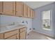 A laundry room with cabinets over a utility sink and natural light from a window at 25057 Riverwalk Dr, Leesburg, FL 34748