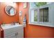 Charming bathroom featuring an orange wall, a white vanity, and a pineapple decor for a tropical ambiance at 3085 Vest Rd, St Cloud, FL 34772