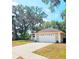 Attached garage of the home with a concrete driveway surrounded by manicured landscaping with mature trees at 513 Rachael Ct, Oviedo, FL 32765
