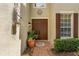 Close-up of a double door entry with brick pavers, lush landscaping, and a decorative wall hanging at 555 Carey Way, Orlando, FL 32825