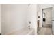 Clean, white tiled bathtub and shower with a view of the light wood hallway flooring at 555 Carey Way, Orlando, FL 32825