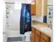 Bathroom featuring wooden cabinets, white tiling, shower-tub combo, and neutral countertops at 6117 Metrowest Blvd # 106, Orlando, FL 32835