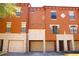 Three-story townhome with tan exterior paint, white garage doors, and multi-pane windows at 6117 Metrowest Blvd # 106, Orlando, FL 32835