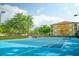 Community tennis court featuring blue surface and green surrounding with nearby buildings at 6117 Metrowest Blvd # 106, Orlando, FL 32835