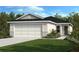 Charming one-story home with a two-car garage, complemented by a lush green lawn and manicured landscaping at 711 Chesnut Ln, Auburndale, FL 33823