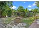 Large, green backyard with a patio, fire pit, and mature trees providing ample shade at 808 Denton Rd, Winter Park, FL 32792
