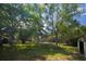 Spacious backyard featuring mature trees and lush green grass, offering privacy and shade at 8735 Rancho Ct, Orlando, FL 32836