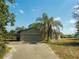 Attached garage with stone accents and a concrete driveway amidst lush greenery and palm trees at 8735 Rancho Ct, Orlando, FL 32836