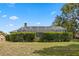 Large, enclosed backyard showcasing a screened-in lanai, mature trees, and a well-maintained lawn with lush perimeter hedge at 10715 Swallow Pt, Clermont, FL 34711
