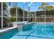 Inviting screened-in pool featuring cool blue water and integrated spa, surrounded by lush landscaping and a sunny sky at 10715 Swallow Pt, Clermont, FL 34711