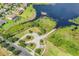 A lovely aerial view of a landscaped entry drive near the lake with a pier on a sunny day at 15160 Avenue Of The Arbors, Winter Garden, FL 34787
