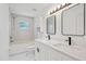 A bright bathroom is equipped with a double vanity, framed mirrors, and tiled shower with tub at 3111 Pine Tree Dr, Edgewater, FL 32141