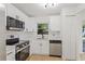 A well-lit kitchen features stainless appliances, white cabinetry, and a window above the sink at 3111 Pine Tree Dr, Edgewater, FL 32141