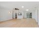 Bright open-concept living room featuring light wood floors, modern lighting fixtures, and access to the kitchen at 3111 Pine Tree Dr, Edgewater, FL 32141