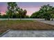 Spacious backyard with a gray brick patio and a white fence surrounded by lush greenery and palm trees at 59 W 10Th St, Apopka, FL 32703